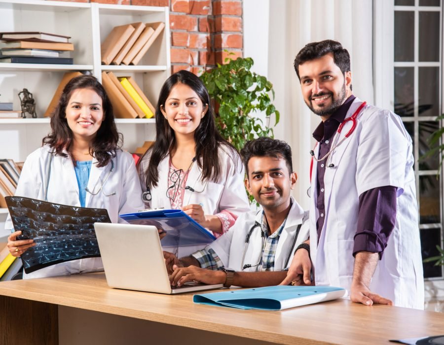 Young Indian asian medical team of doctors using laptop with case papers at work table. Medical professionals in a meeting with computer, speaking, listening or celebrating success